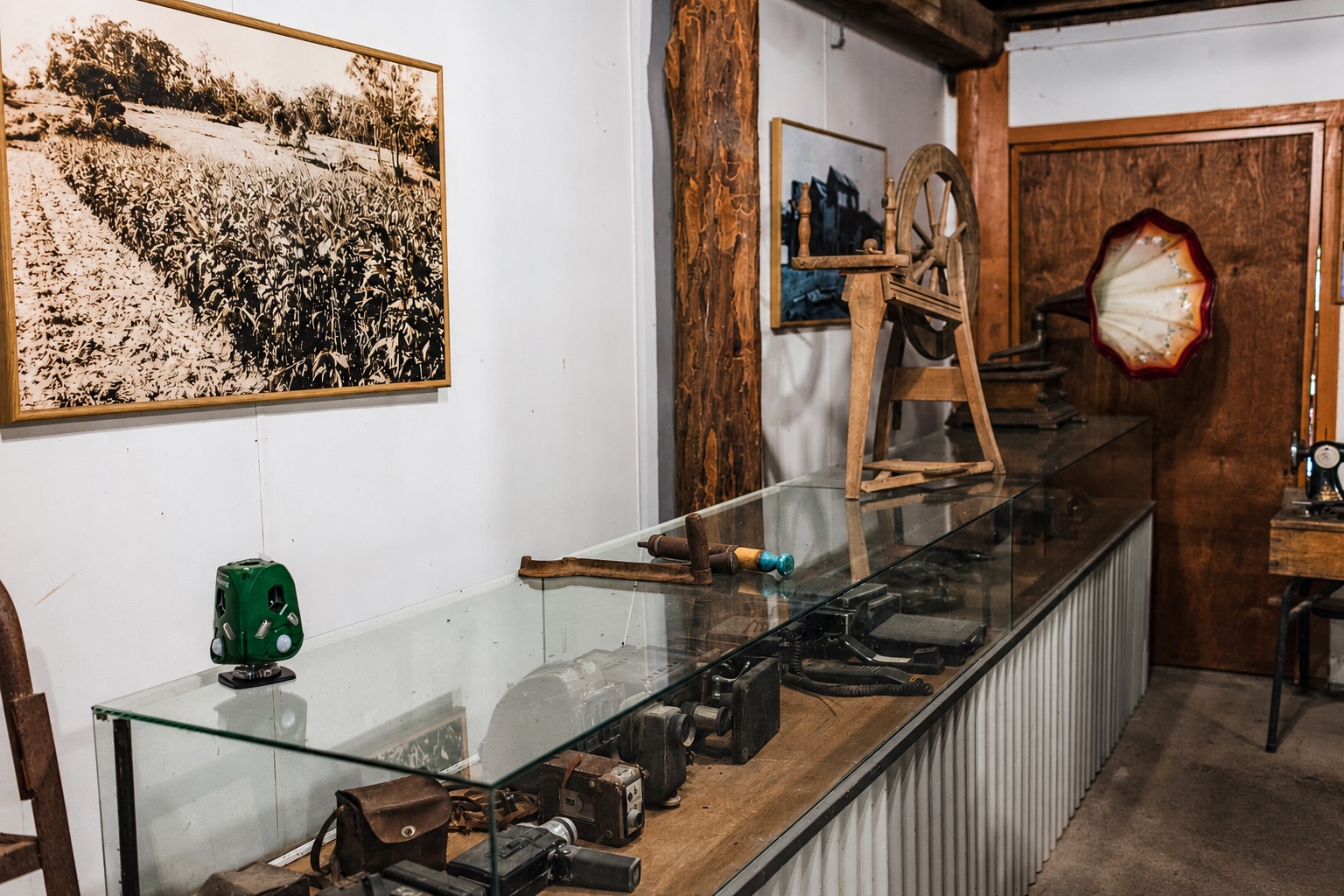 Display cases of vintage cameras, a spinning wheel and a gramophone inside the Historic Rivermill museum