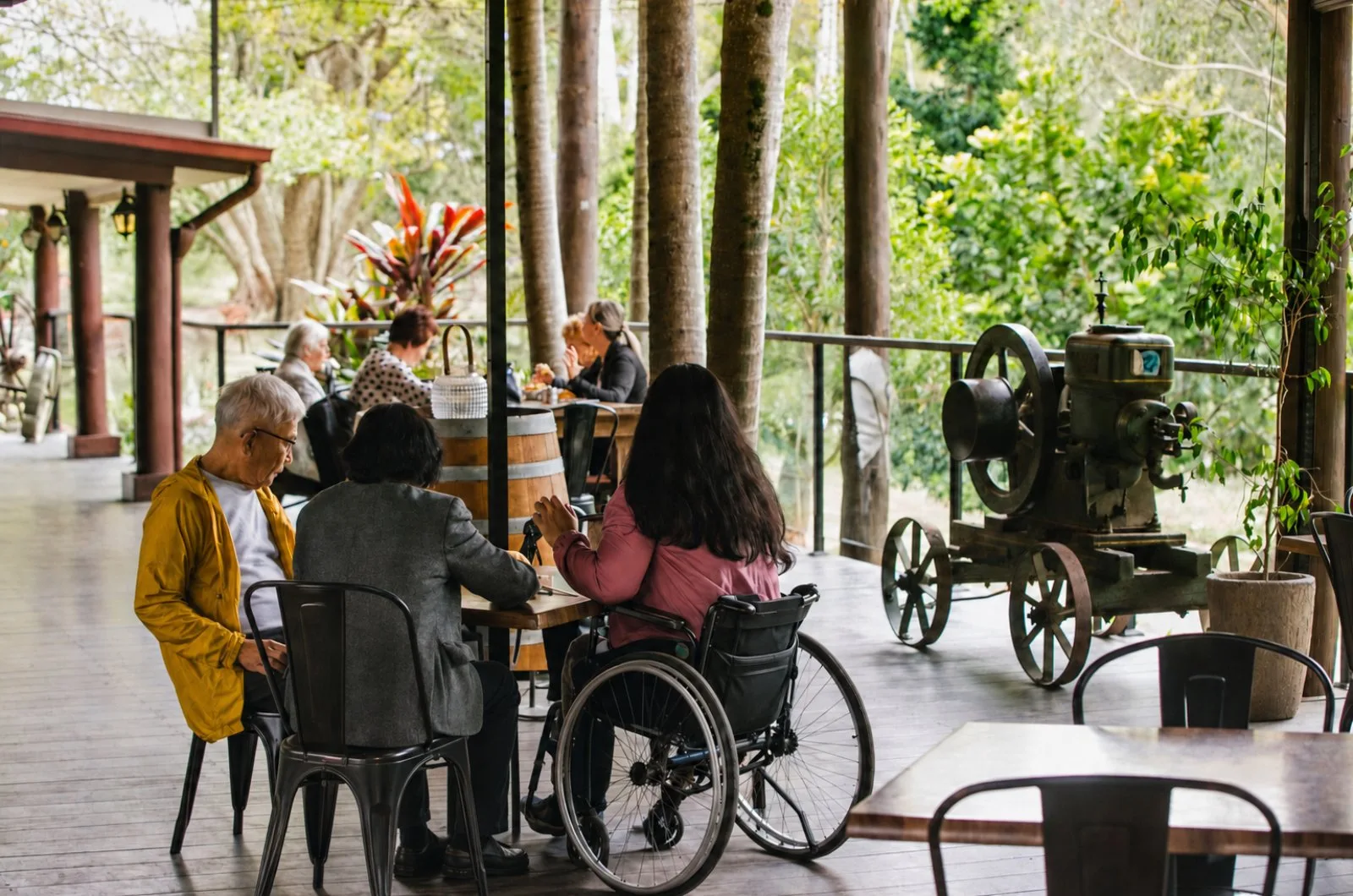 Guests, one using a wheelchair, sharing a meal on the café deck at Historic Rivermill